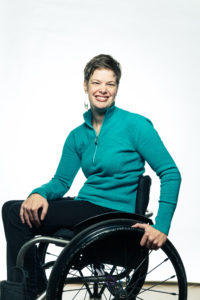 Portrait of Meghan Sellet, director of TCNJ's Accessibility Resource Center. Meghan is shown sitting in her wheelchair wearing a green top and black pants.