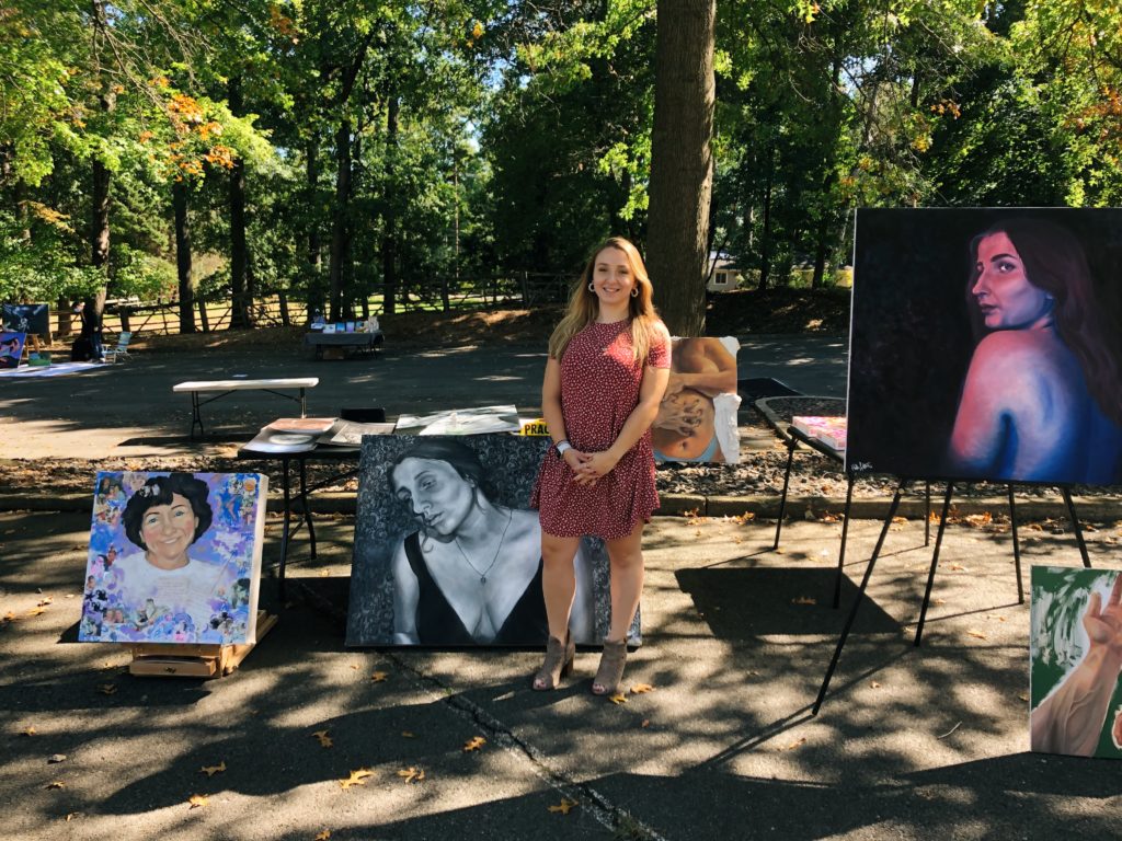 Halle Luttrell in front of some art pieces at her open-air art gallery.