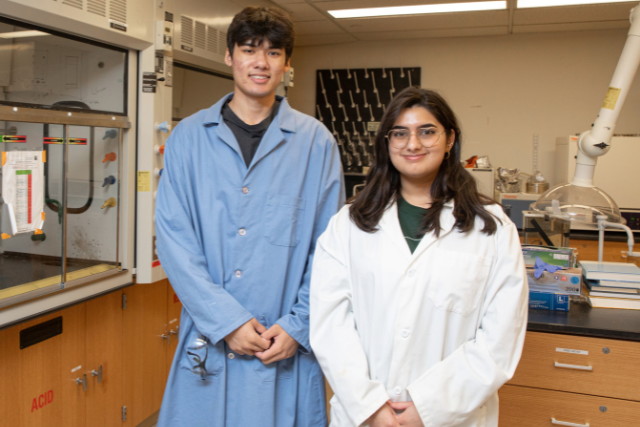 two students in a chemistry lab wearing lab coats